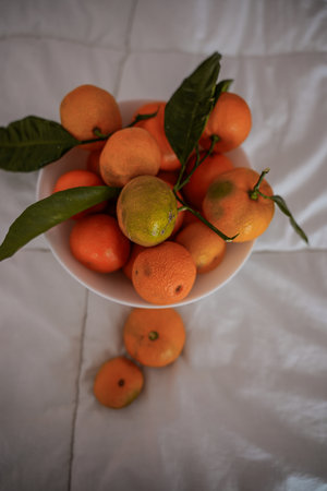 A plate with tangerines and two tangerines next to the plate, view from aboveの写真素材
