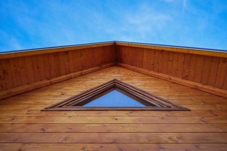 Horizontal view of wooden house gable with window against blue skyの写真素材