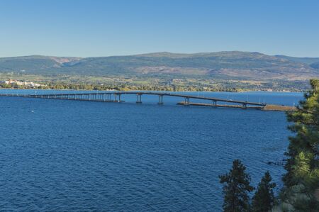 A view of the bridge over Okanagan Lake between West Kelowna and Kelowna British Columbia Canada with a view of the mountains in the backgoundの写真素材