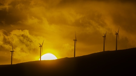 Wind turbines against an orange sunset at Maui Hawaii USAの写真素材