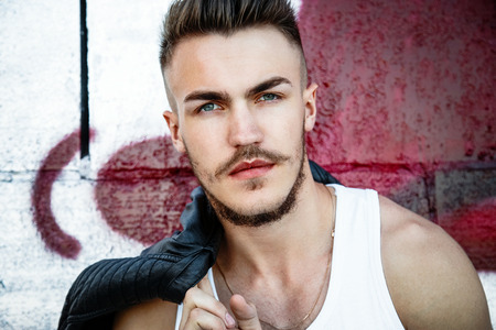 Portrait of attractive young man in a white shirt outdoorsの写真素材