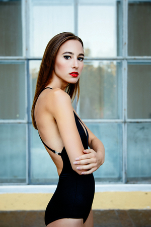 Beautiful young girl posing on street over glass wall backgroundの写真素材