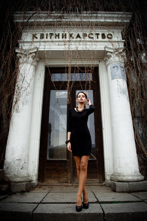 Sensual pretty brunette female model wearing black dress posing over old buildingの写真素材