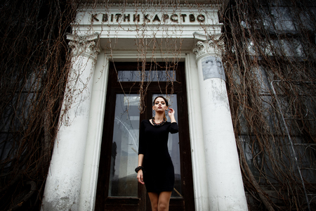 Sensual pretty brunette female model wearing black dress posing over old buildingの写真素材