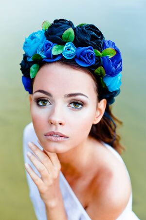 Sensual sexy woman wearing floral wreath standing in waterの写真素材