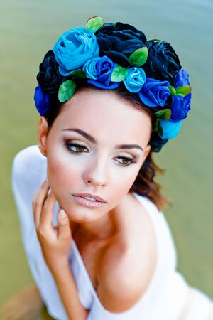 Sensual sexy woman wearing floral wreath standing in waterの写真素材