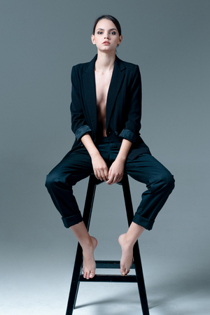Cute brunette woman wearing a jacket over naked body sitting on the chairの写真素材