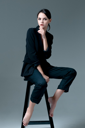 Cute brunette woman wearing a jacket over naked body sitting on the chairの写真素材
