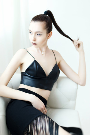 Pretty woman in black skirt on a white sofaの写真素材