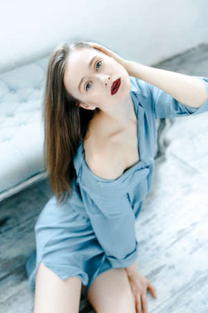 Pretty sensual woman in a blue shirt on vintage sofaの写真素材