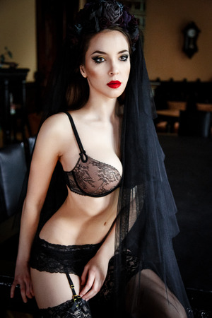Beautiful woman in stockings and lingerie with a wreath on head. Beauty female. Perfect skin and make up. Red lipsの写真素材