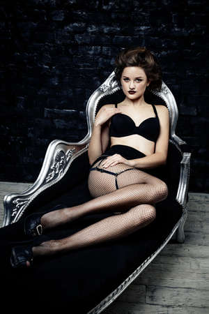 Sexy brunette woman in black lingerie sitting on the sofaの写真素材