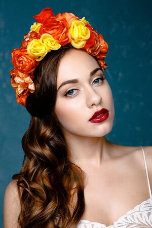 Portrait of a beautiful young woman in a wreath on her head. Bright make-up with sexy red lips and perfect skinの写真素材