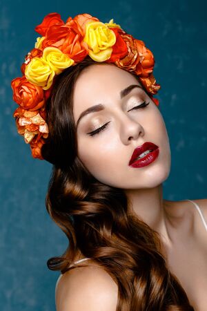 Portrait of a beautiful young woman in a wreath on her head. Bright make-up with sexy red lips and perfect skinの写真素材