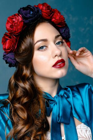 Portrait of a beautiful young woman in a wreath on her head. Bright make-up with sexy red lips and perfect skinの写真素材