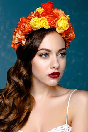 Portrait of a beautiful young woman in a wreath on her head. Bright make-up with sexy red lips and perfect skinの写真素材