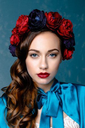 Portrait of a beautiful young woman in a wreath on her head. Bright make-up with sexy red lips and perfect skinの写真素材