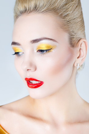 Pretty blonde female model face with artistic make up. Woman with red lips, white hair and pale skinの写真素材