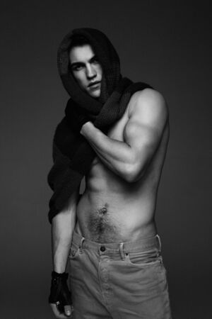 Young fashion topless man in knitted scarf on his had isolated on dark background. black and white photoの写真素材