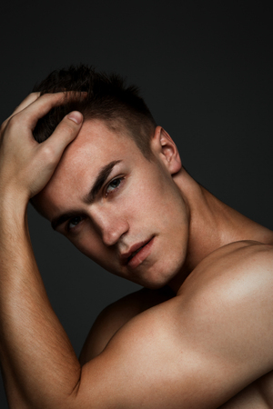Fashion man portrait with his hand in his hair on dark backgroundの写真素材
