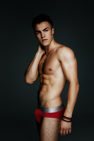 Young fashion topless man isolated on dark background. Strong Athletic Man Fitness Model Torso showing six pack absの写真素材