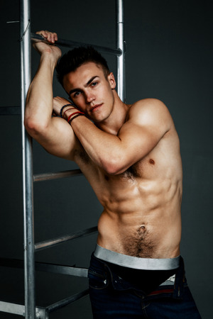 Young fashion topless man isolated on dark background. Strong Athletic Man Fitness Model Torso showing six pack absの写真素材