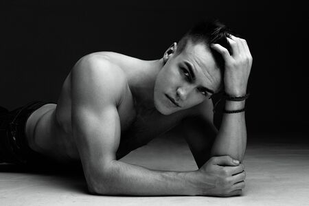 Fashion man portrait with his hand in his hair on dark background black and white photoの写真素材
