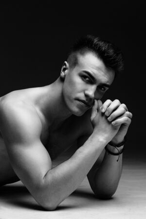 Portrait of a handsome topless man inflated lying on the floor on dark background black and white photoの写真素材