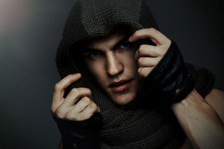 Fashion man portrait wearing knitted scarf on had on dark backgroundの写真素材