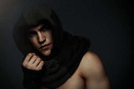 Fashion man portrait wearing knitted scarf on had on dark backgroundの写真素材