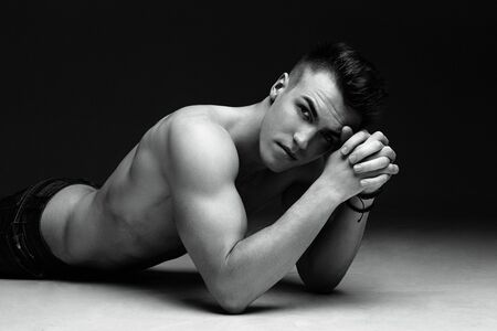 Portrait of a handsome topless man inflated lying on the floor on dark background black and white photoの写真素材