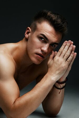 Portrait of a handsome topless man inflated lying on the floor on dark backgroundの写真素材
