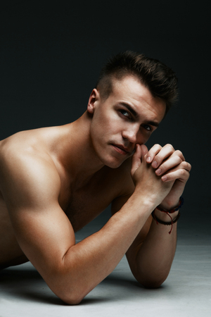 Portrait of a handsome topless man inflated lying on the floor on dark backgroundの写真素材