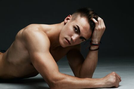 Fashion man portrait with his hand in his hair on dark backgroundの写真素材
