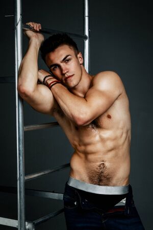 Young fashion topless man isolated on dark background. Strong Athletic Man Fitness Model Torso showing six pack absの写真素材