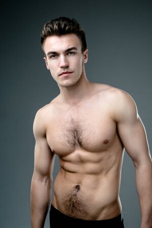 Young fashion topless man isolated on dark backgroundの写真素材