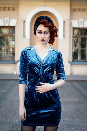 Beautiful young girl in blue dress posing on street over building backgroundの写真素材