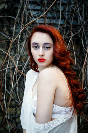 Beautiful young redhead girl posing outdoorsの写真素材