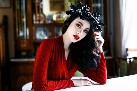 Beautiful model with a rad and black wreath of flowers on her headの写真素材
