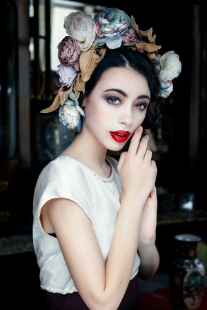 Portrait of a beautiful young woman in a wreath on had. beauty girl with red lips. Female face with clear skin close-up. Skincareの写真素材