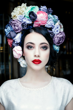 Portrait of a beautiful young woman in a wreath on had. beauty girl with red lips. Female face with clear skin close-up. Skincareの写真素材
