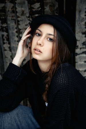beautiful young woman lady posing outdoors wearing black hatの写真素材