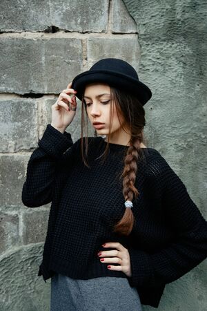beautiful young woman lady posing outdoors wearing black hatの写真素材