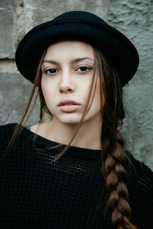 beautiful young woman lady posing outdoors wearing black hatの写真素材