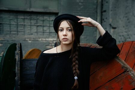 beautiful young woman lady posing outdoors wearing black hatの写真素材