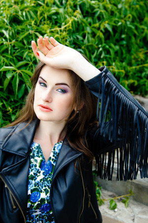 Glamorous young woman in black leather jacket outdoorsの写真素材