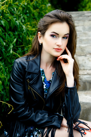 Glamorous young woman in black leather jacket outdoorsの写真素材