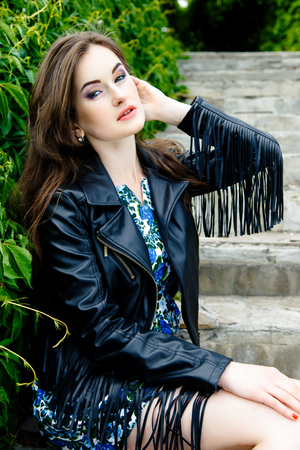 Glamorous young woman in black leather jacket outdoorsの写真素材