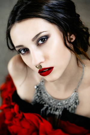 Beautiful woman with cute face bright make up red lips and piercing on noseの写真素材
