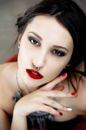 Beautiful woman with cute face bright make up red lips and piercing on noseの写真素材